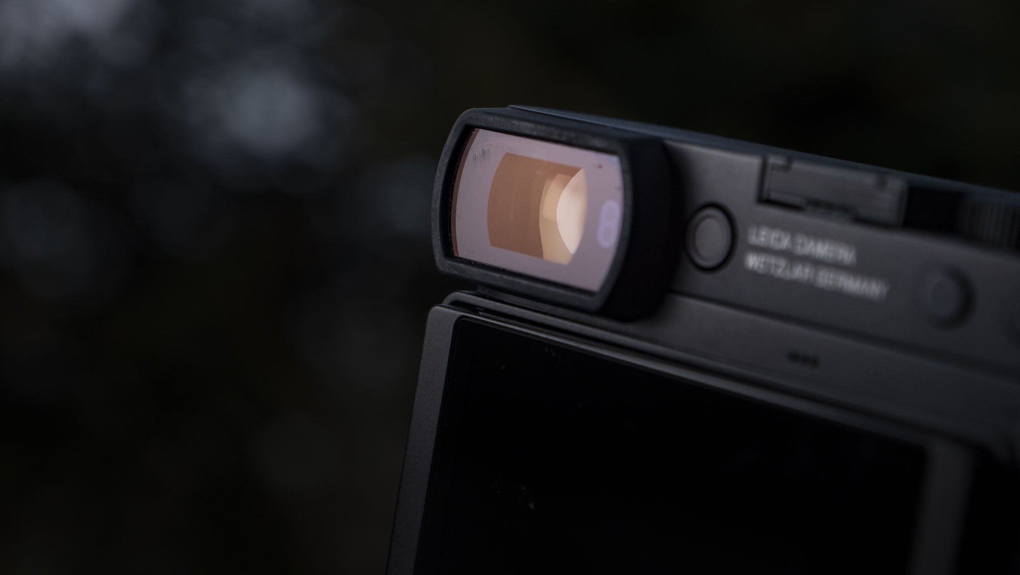 Leica Q3 Monochrom compact camera outside on a snow-dusted log