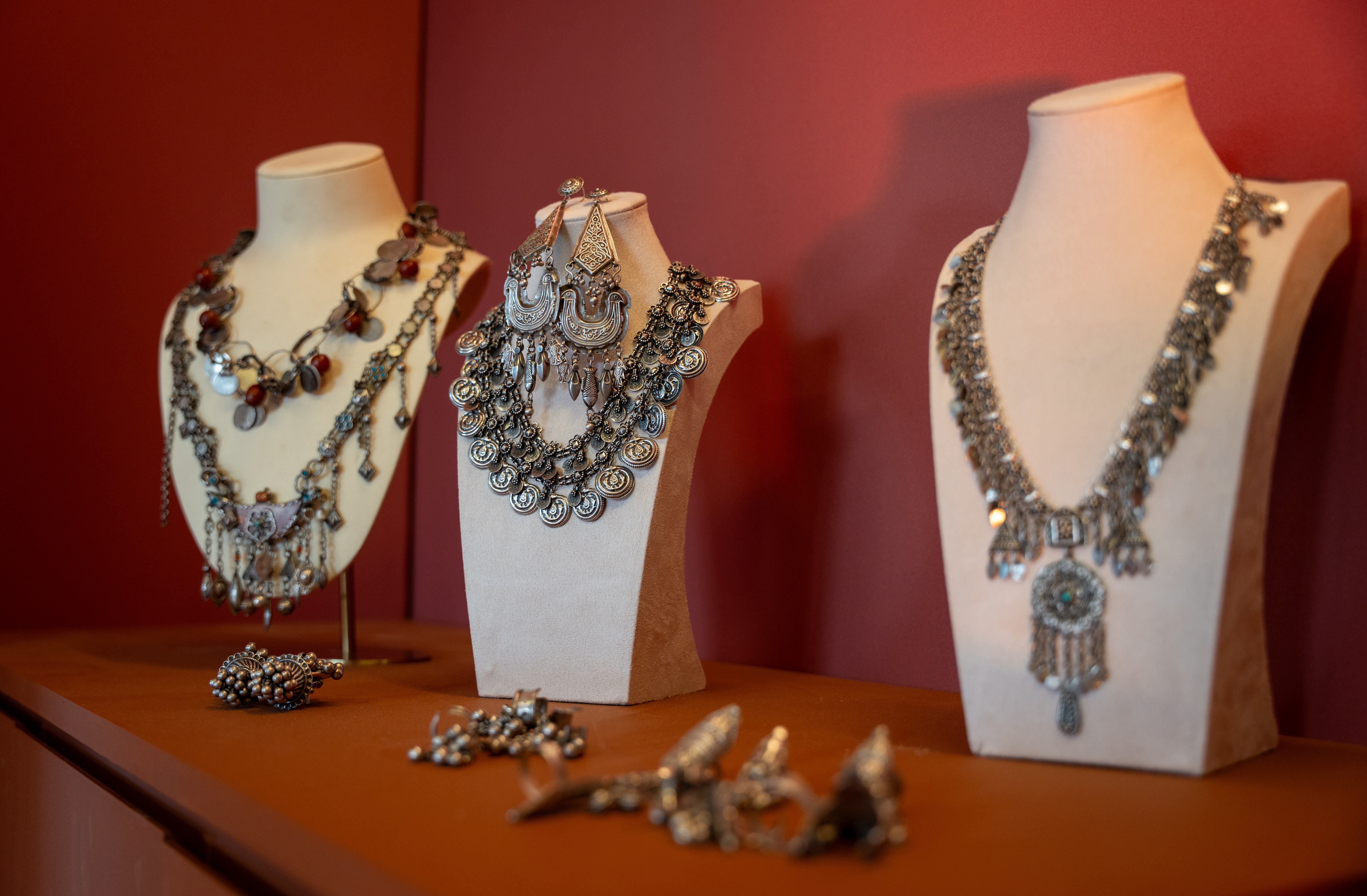 Three silver necklaces displayed on stands