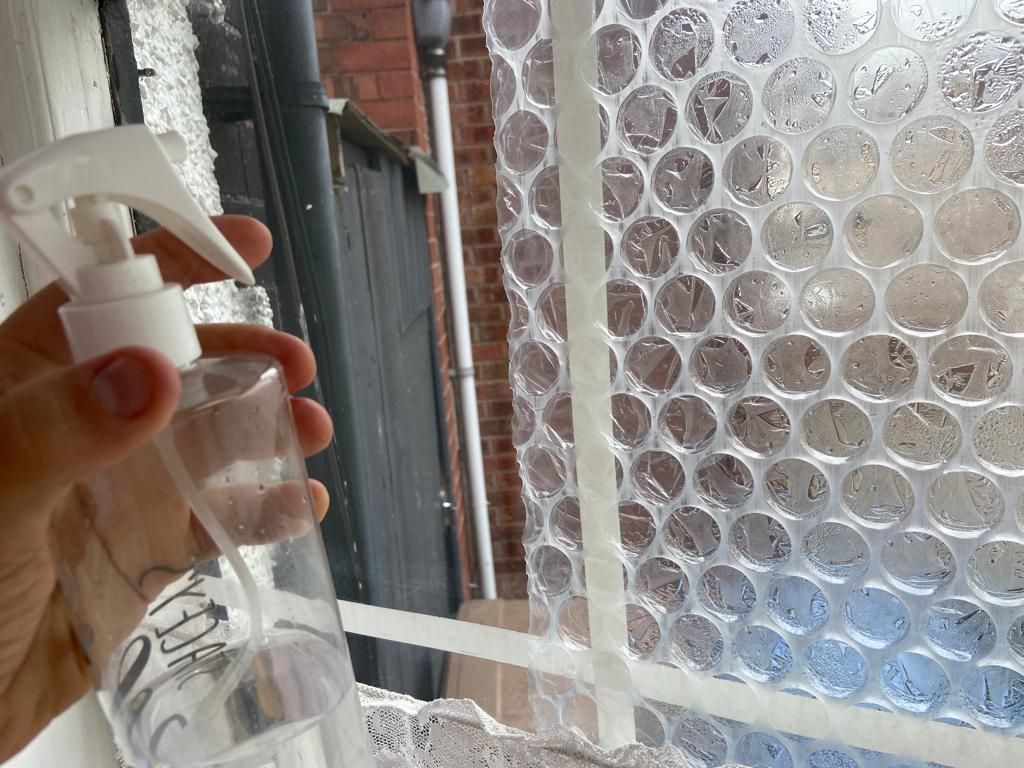 Spraying the bubble wrap with water to make it stick
