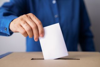 A man putting a slip of paper in a ballot box