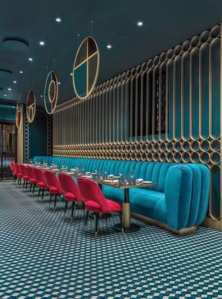 Liòn restaurant with teal banquette seating, red chairs and circles of brass as wall screens