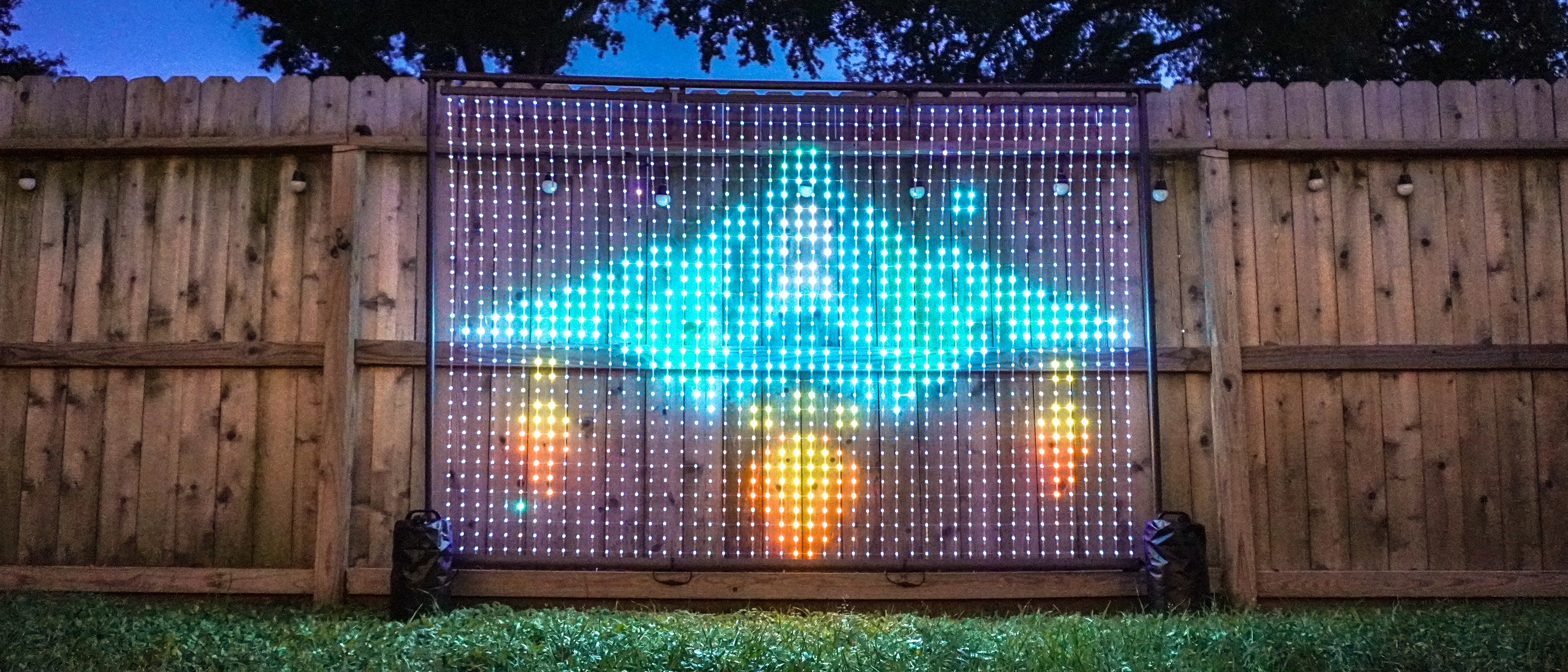 The Govee Lightwall set up in a backyard next to a fence showing a GIF of a spaceship flying through the cosmos