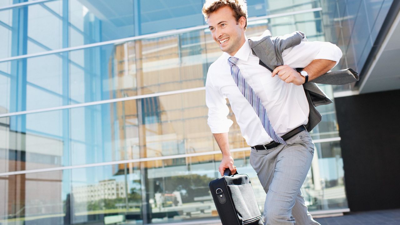 Businessman running out of the office carrying a briefcase and smiling