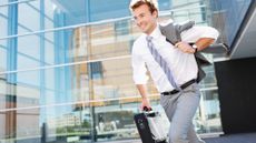 Businessman running out of the office carrying a briefcase and smiling