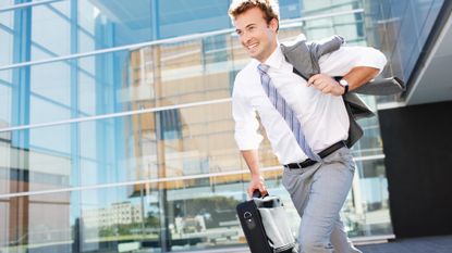 Businessman running out of the office carrying a briefcase and smiling