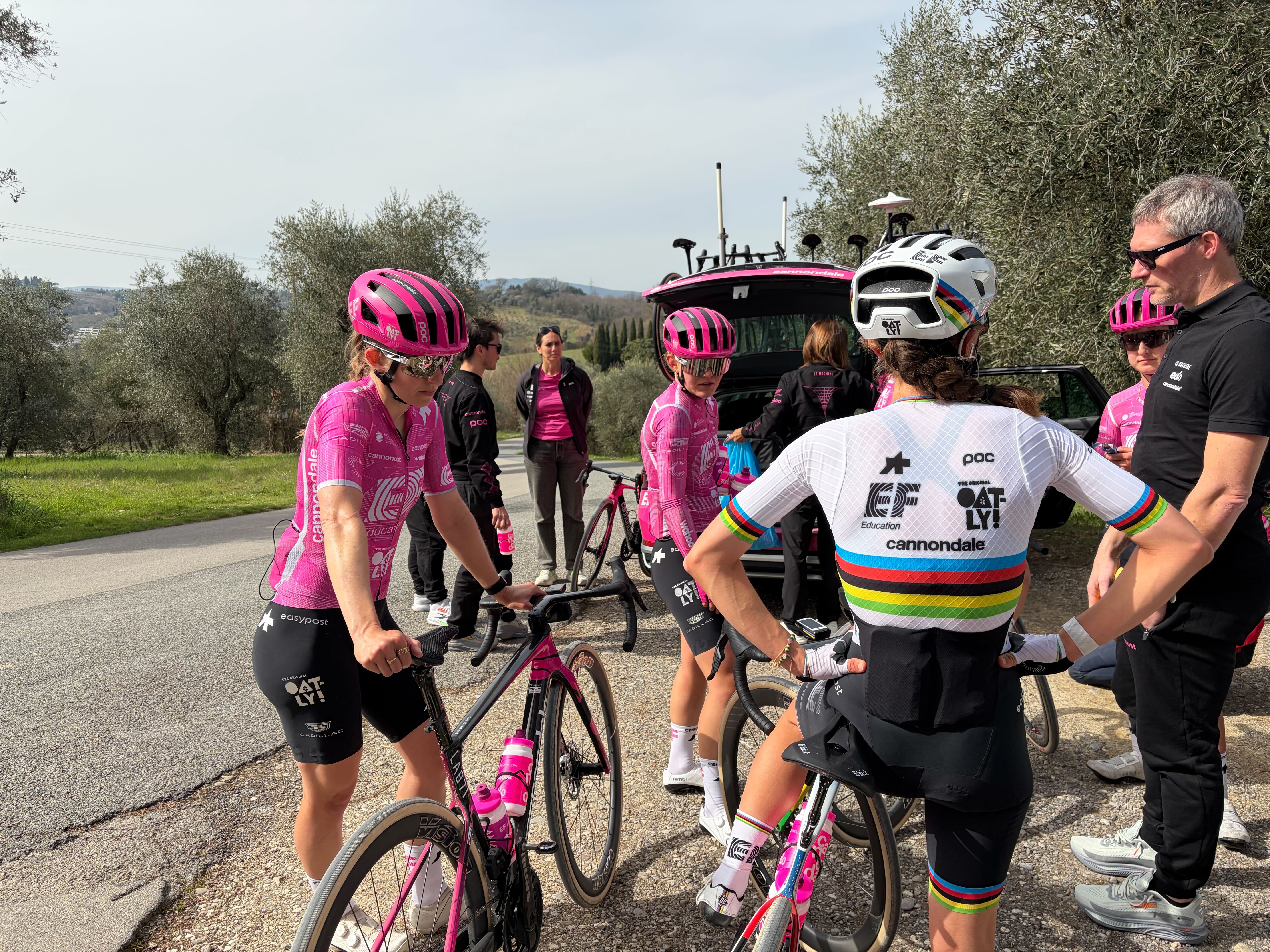 La campeona del mundo Magdeleine Vallières, de espaldas a la cámara, en un grupo detrás del coche del equipo