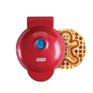 A red waffle maker with a gingerbread person waffle