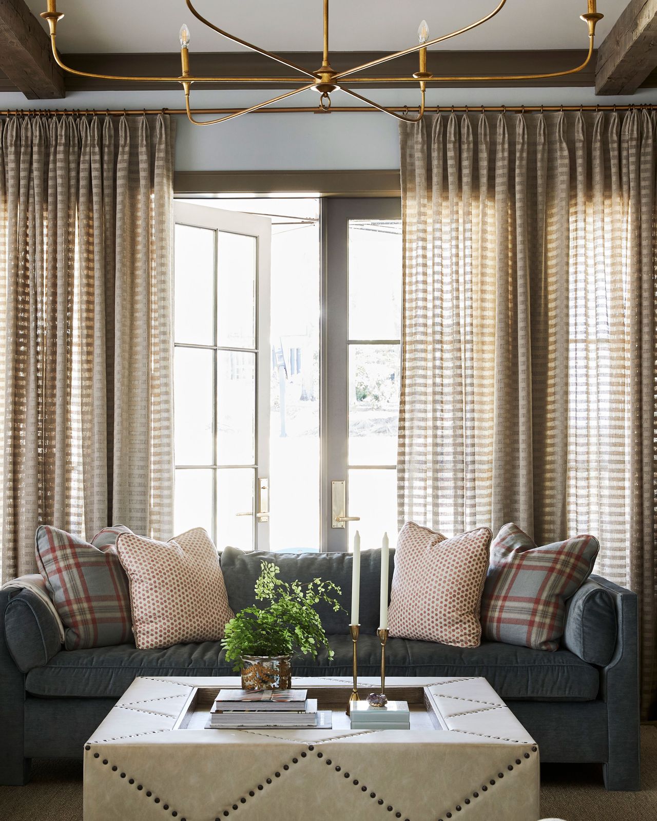 living room with blue sofa and multipaned french window and ceiling beams with modern chandelier