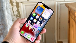 iphone 13 pro display on in hand with wood background