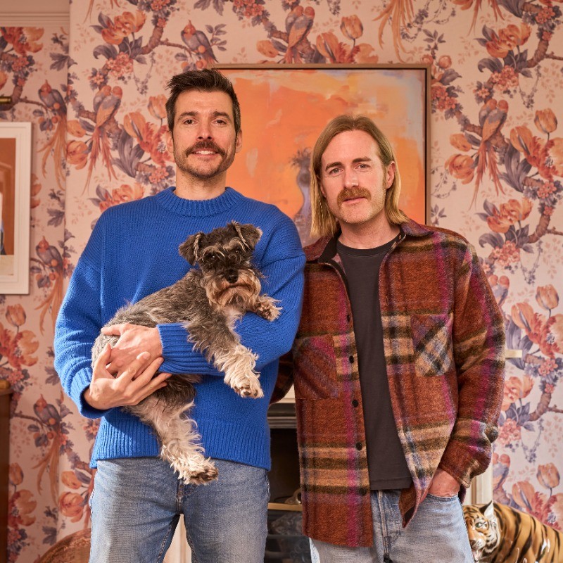 Photo of the two male founders of Divine Savages holding their schnauzer dog