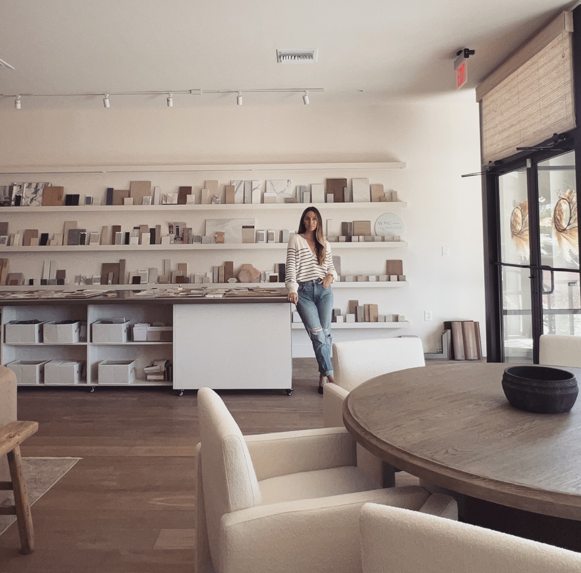 a woman standing in a large room with shelves of material samples