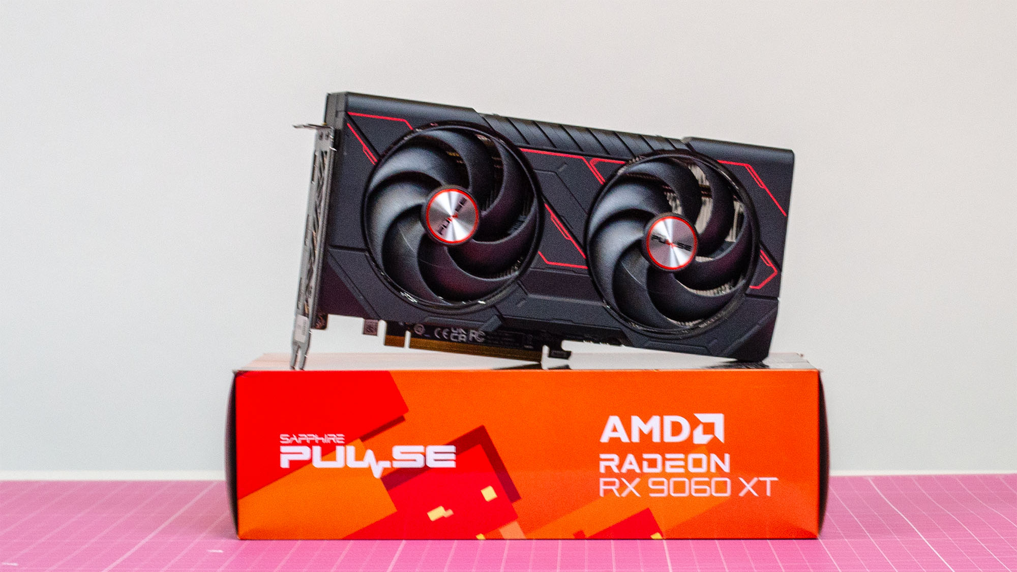 An AMD Radeon RX 9060 XT on top of its retail packaging on a table