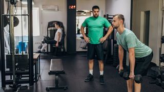 Man does deadlift dumbbell leg exercise in gym