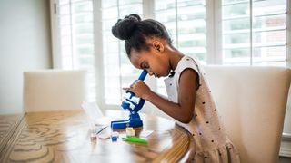 A pre-school girl using one of the best microscopes for kids
