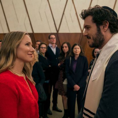 Kristen Bell as Joanne and Adam Brody as Noah, standing in front of congregants at a synagogue, in episode 102 of Nobody Wants This.