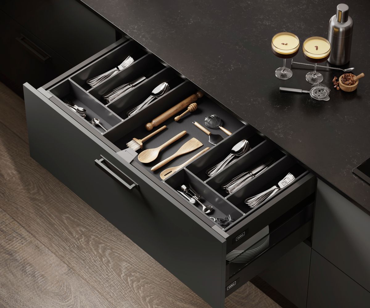 open dark grey kitchen drawer with divided storage inside displaying utensils