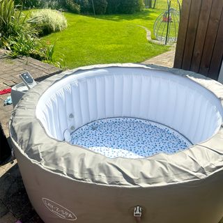 The grey inflatable Lay-Z-Spa Barbados hot tub outside in a garden on a sunny day