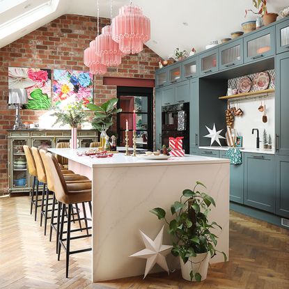 green kitchen with island and pink pendant lights and christmas decorations