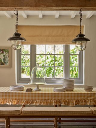 dining area with gingham tablecloth pedant lights and yellow stipe blind