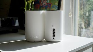 TP-Link Deco XE75 nodes showing front and back near a window