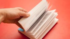 A hand flips the pages of a book.