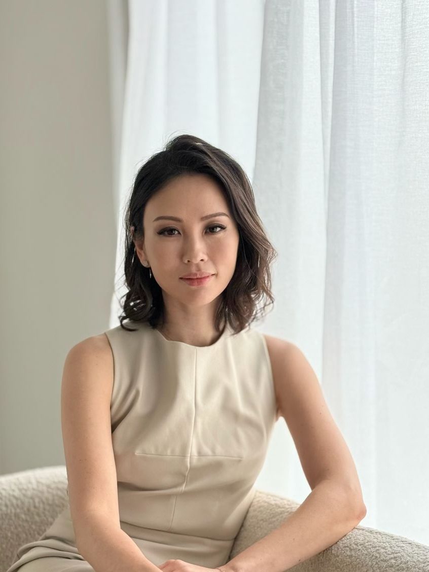 an asian woman in a cream dress with short brown hair looking at the camera