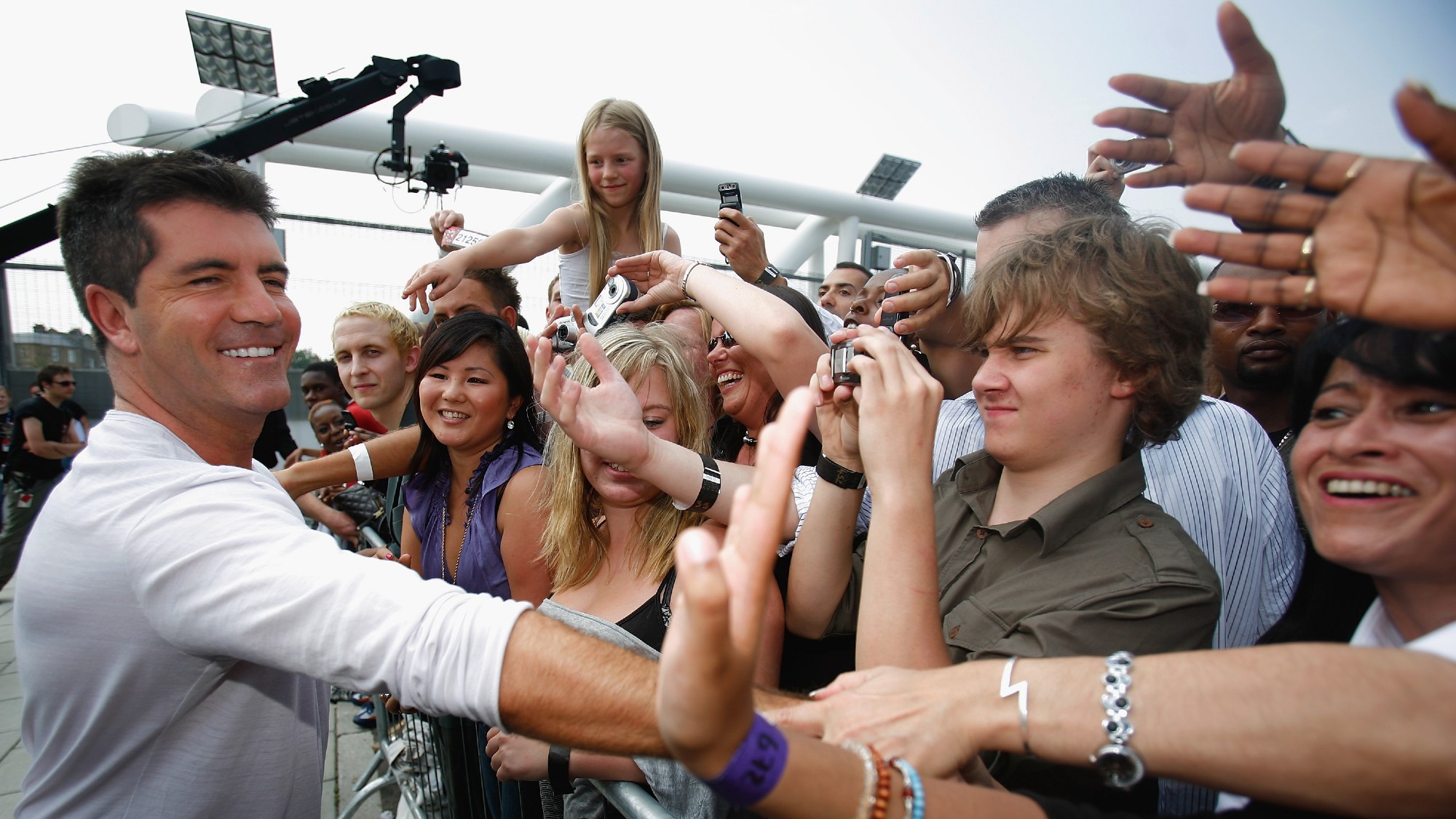 Simon Cowell interacts with crowd members as he arrives during the first day of auditions for X Factor, Series 4 at Arsenal Emirates Stadium