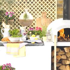 outdoor kitchen with pizza oven and pots of herbs and flowers