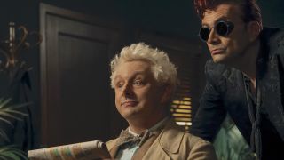 Aziraphale holding newspaper while Crowley stands over his shoulder in Good Omens Season 3