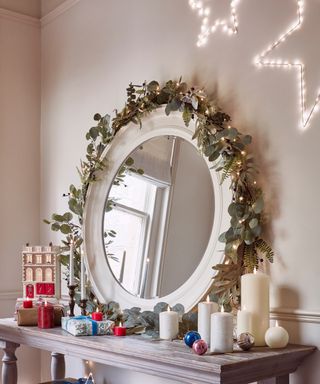 christmas garland around a mirror on a console table with Christmas decorations - Lights4Fun