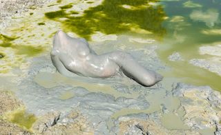 nude female body in mud pool