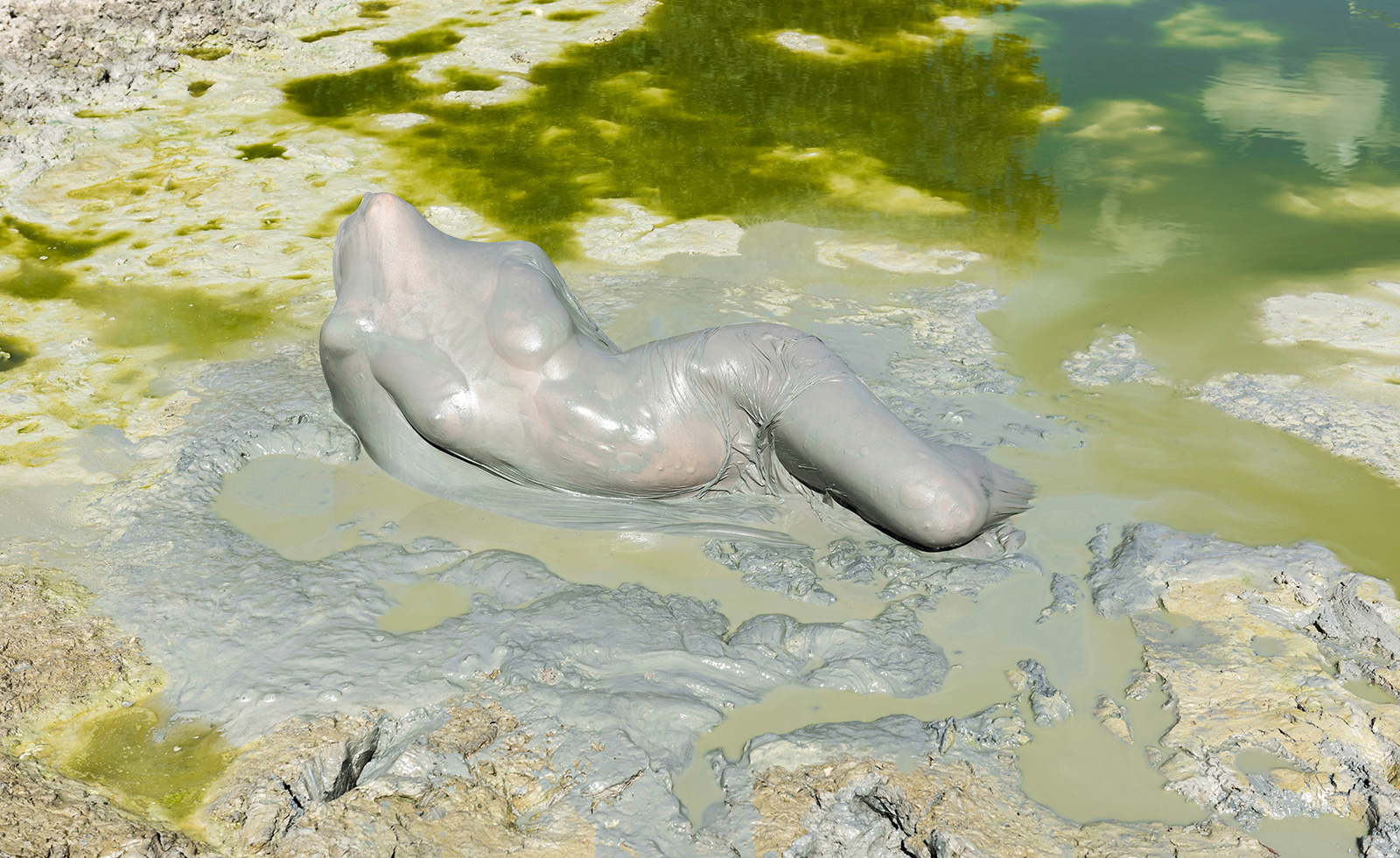 nude female body in mud pool