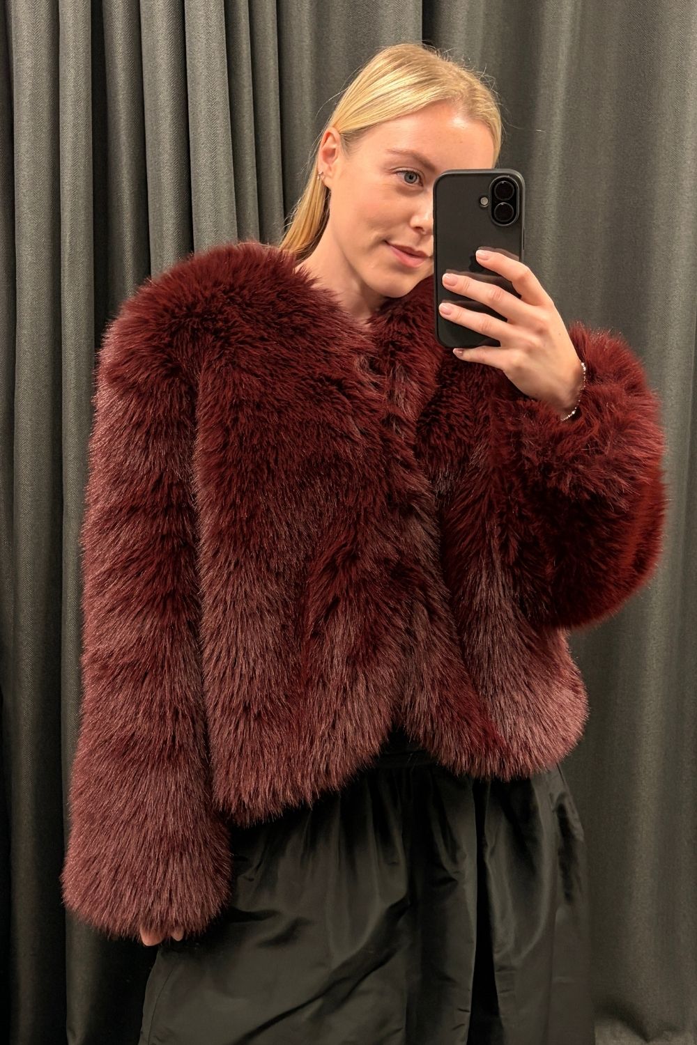 Florrie wears a burgundy faux fur coat, black skirt from the John Lewis X Rixo collaboration
