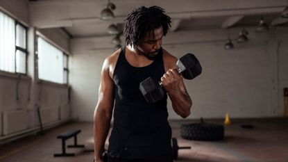 A man performing a biceps curl with dumbbells as part of a home workout