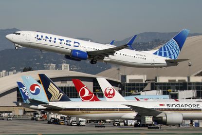 A United Airlines plane takes off from an airport where other planes are taxiing.