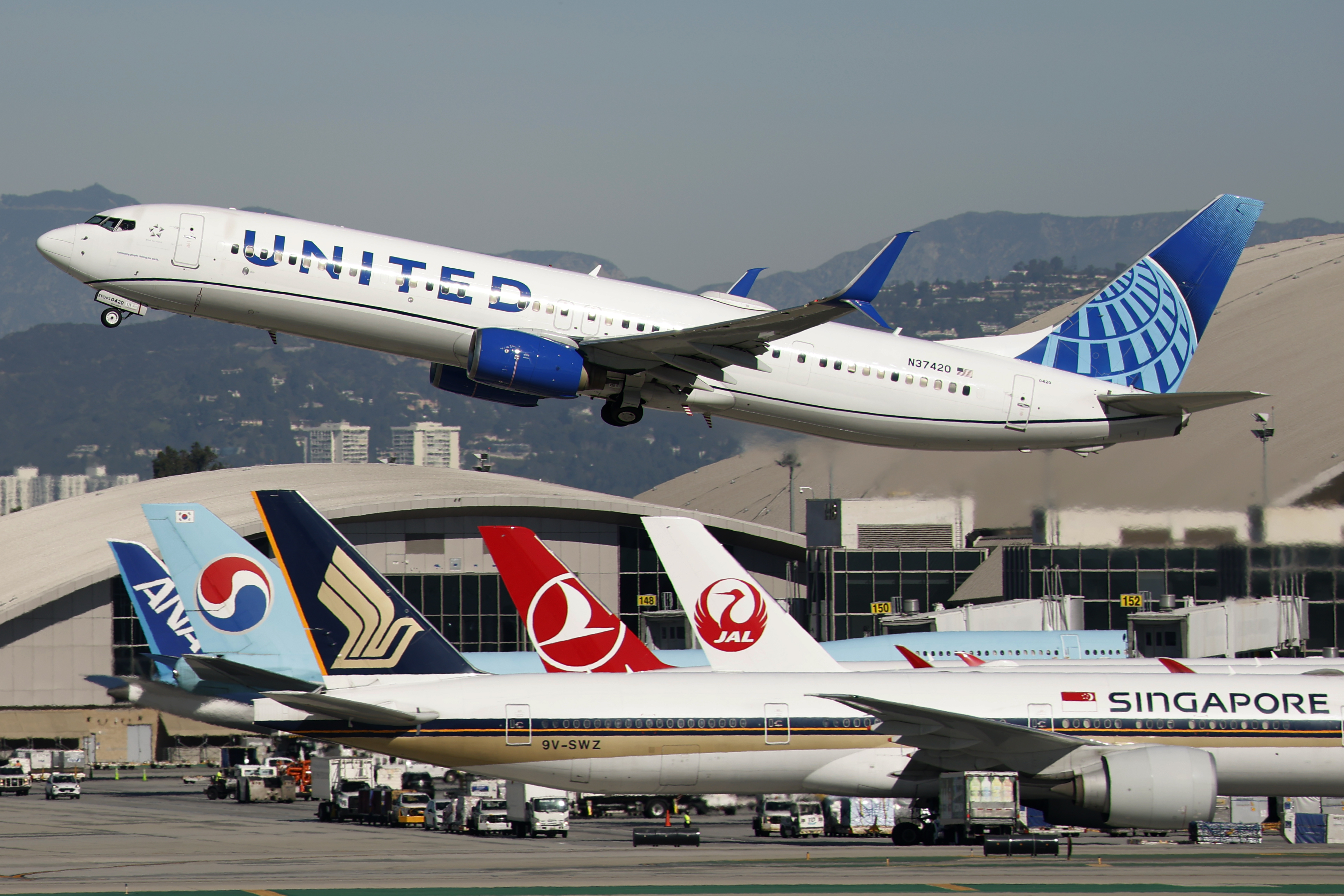 A United Airlines plane takes off from an airport where other planes are taxiing.