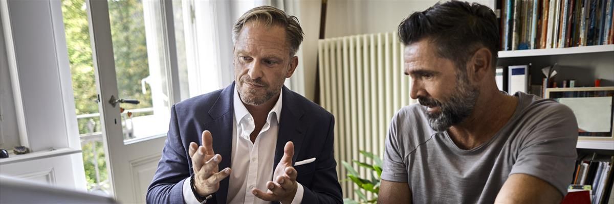 Two adult men talking and looking at a computer screen