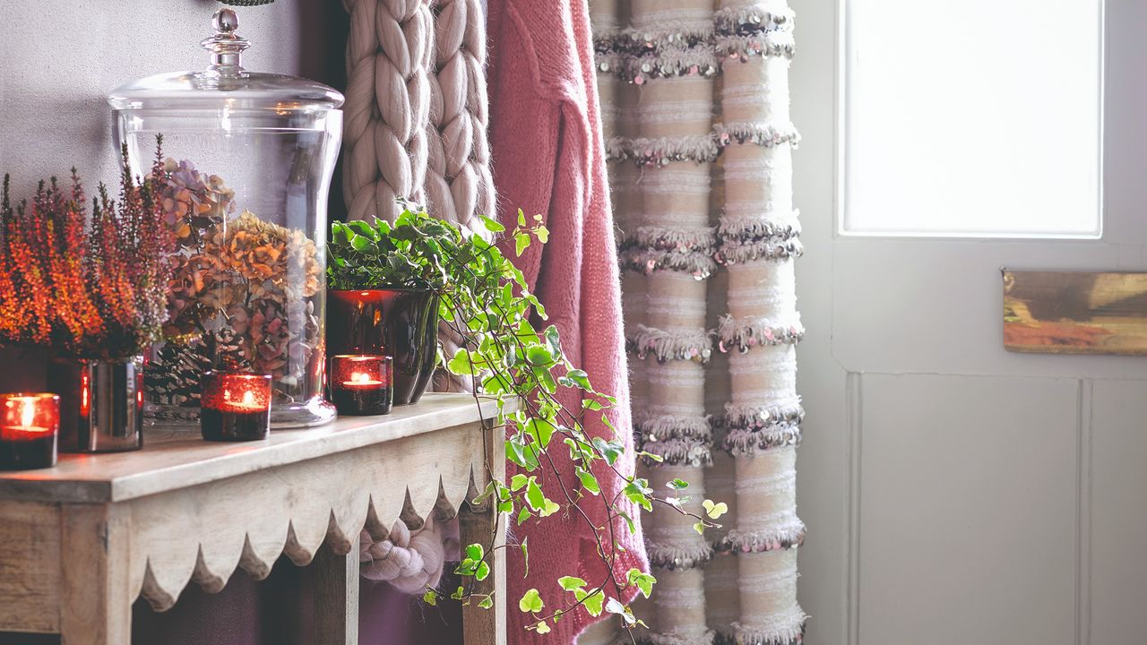 A hallway with a scalloped console table displaying plants and tea lights