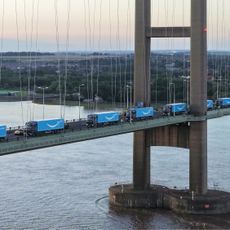 A fleet of Amazon trucks on a bridge over water