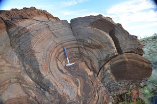 Despite a possibly thin atmosphere on early Earth, researchers found evidence of single-celled photosynthetic life on the shore of a large lake, as seen in this 2.7-billion-year-old stromatolite from Western Australia.