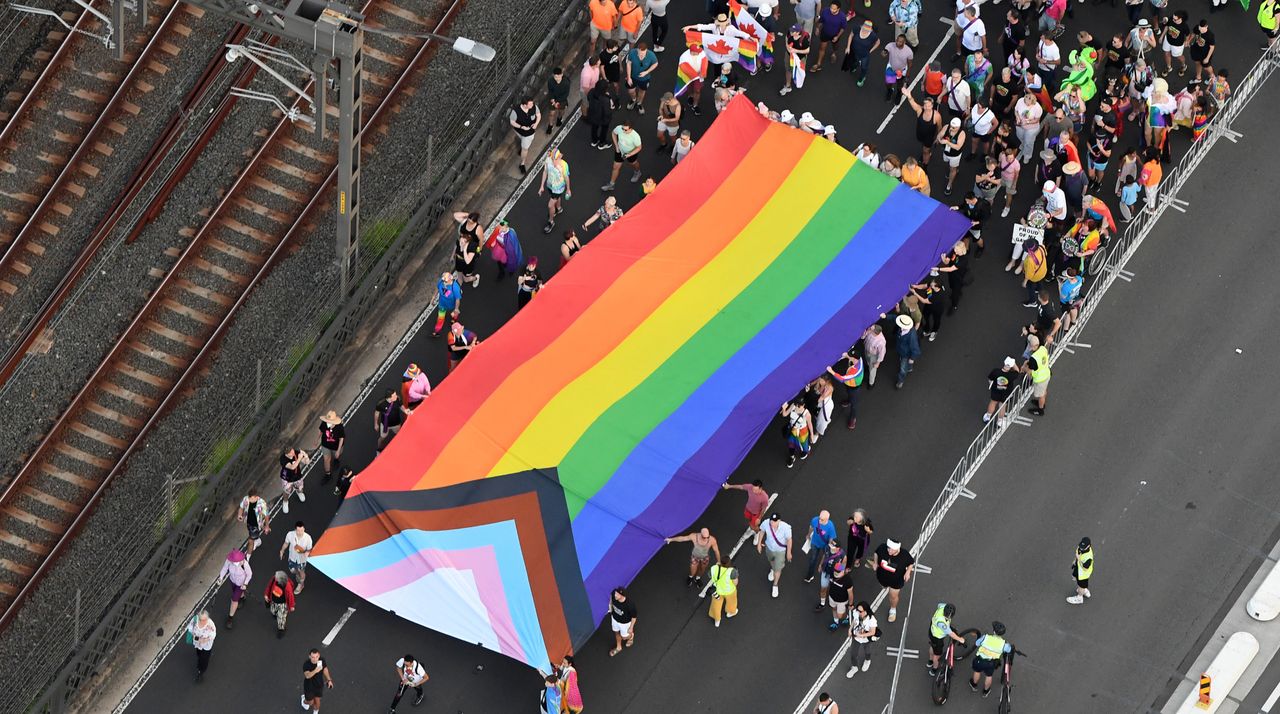 In this aerial view, the Progress Pride flag is carried over the Sydney Harbour Bridge as people take part in Pride March on March 05, 2023 in Sydney, Australia.