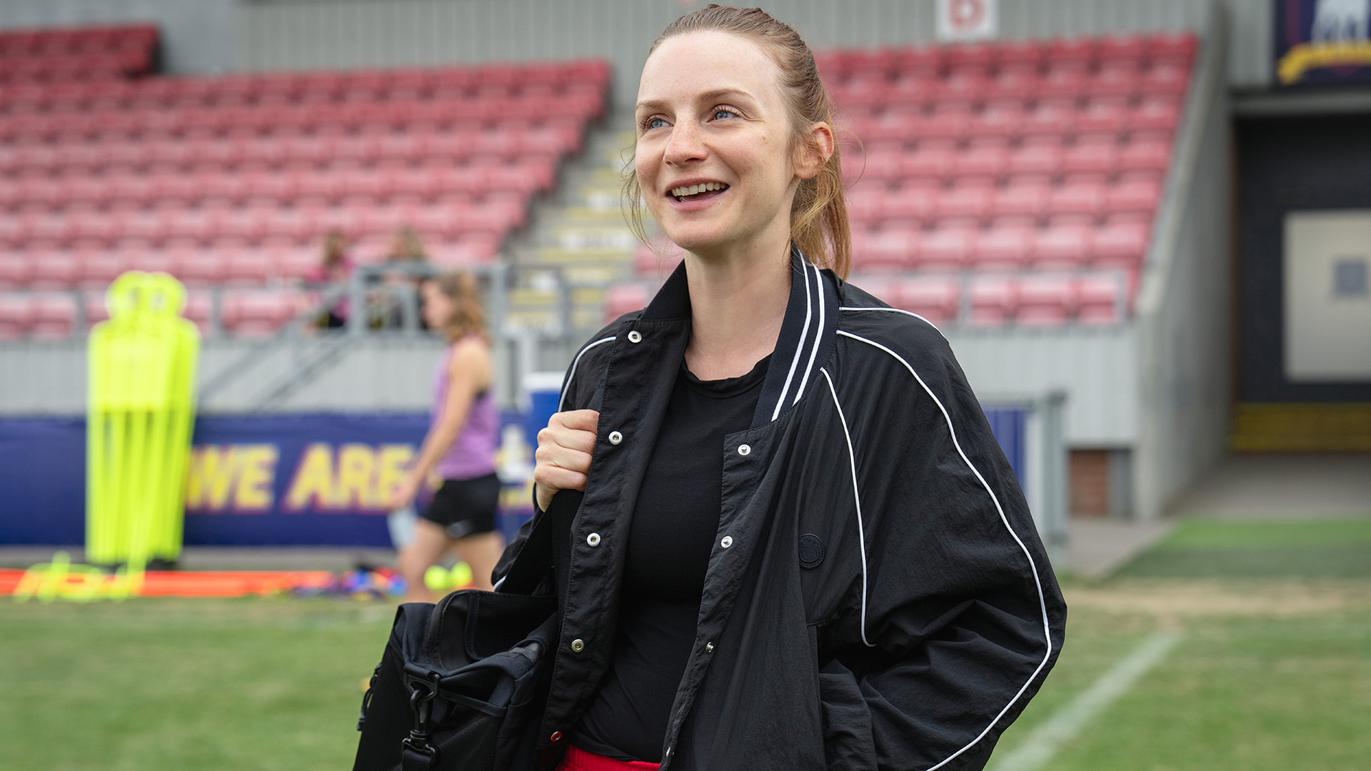Faye Marsay's Lizzie smiling and holding a sports bag in Ted Lasso season 4