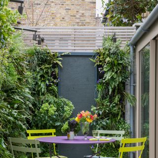 Courtyard with metal table and chairs, living walls and spotlights