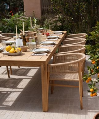 Outdoor dining set up with wooden table, candles, lemons