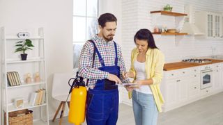 A professional pest control service man with a woman in the kitchen
