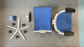 A deconstructed ErgoChair Plus chair, on an office floor.