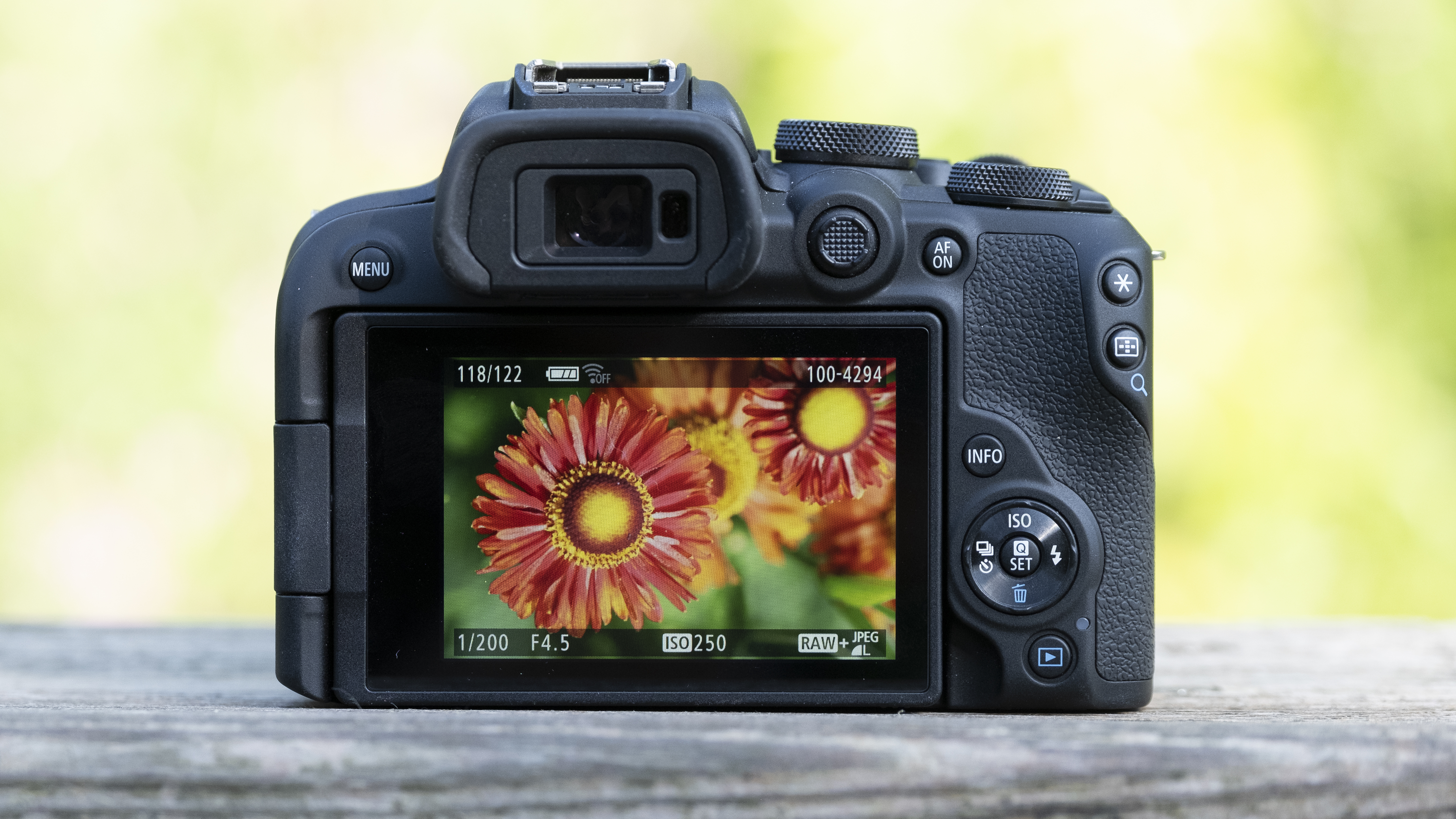 The Canon EOS R10 camera sitting on a wooden bench