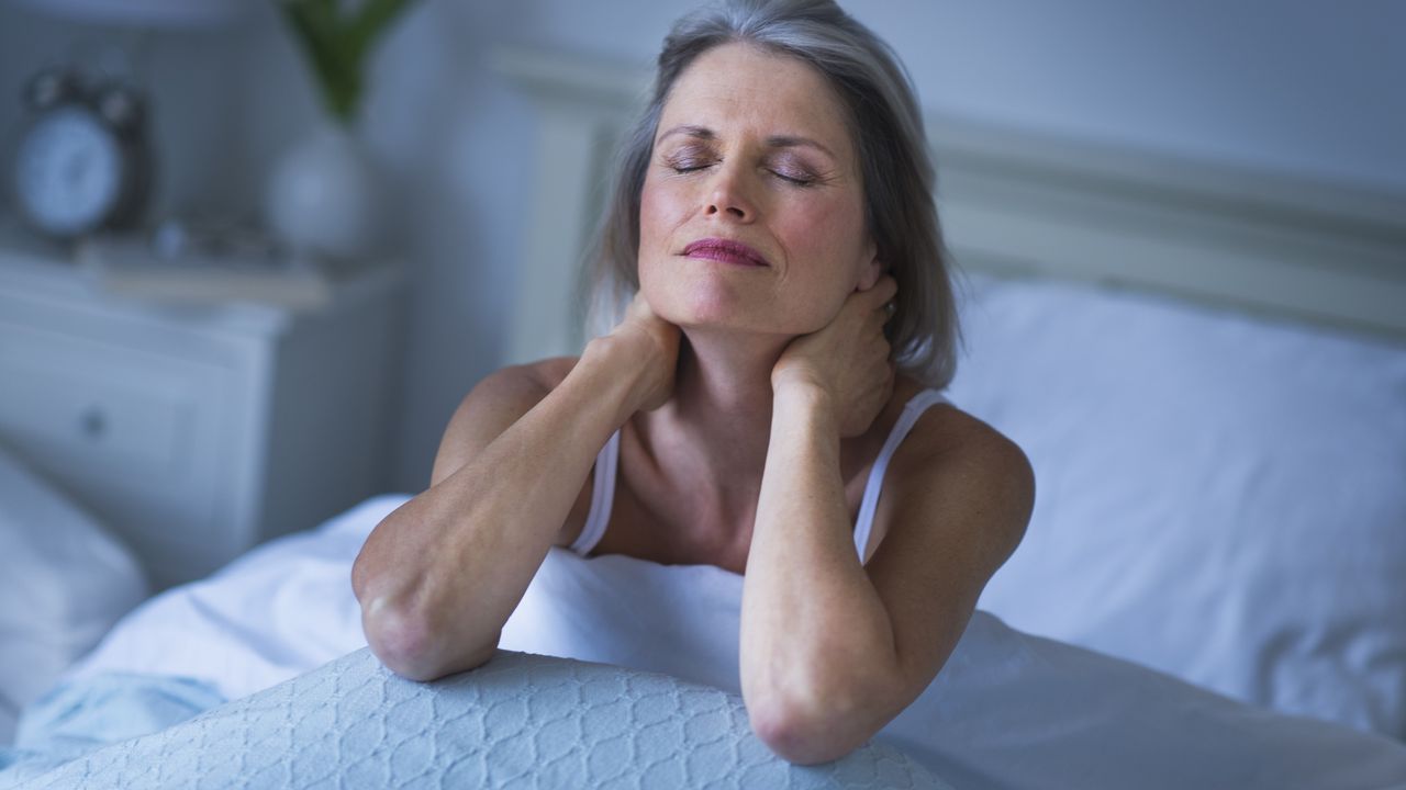 An older woman sits up in bed, unable to sleep.