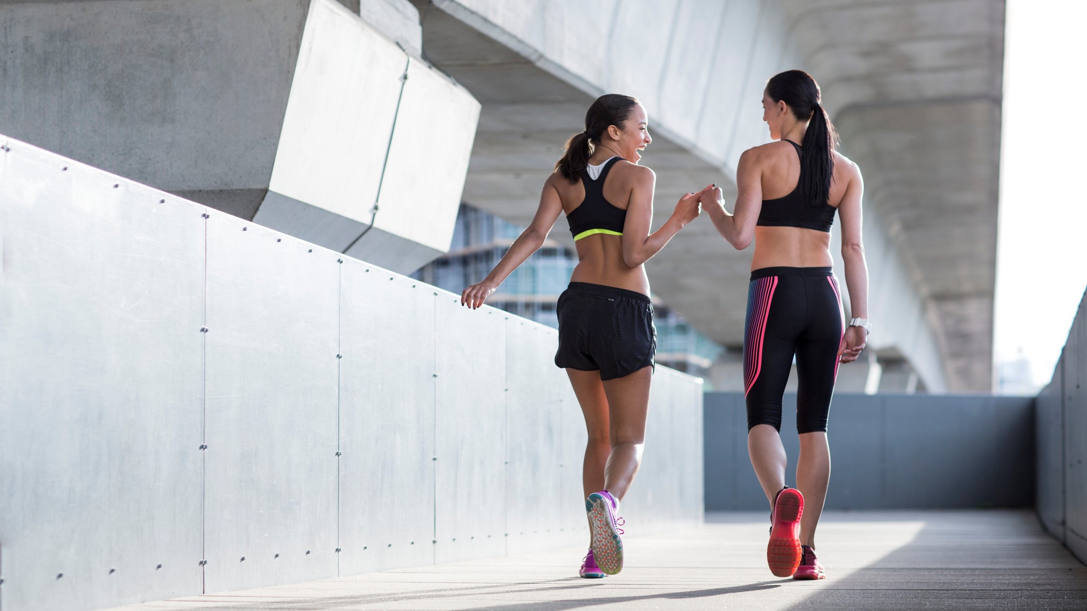 Photo of two women walking wearing sports bras