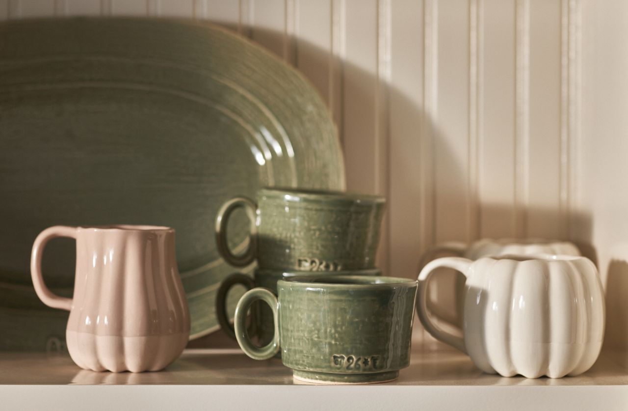 A kitchen with pumpkin-shaped mugs, a water jug and plates